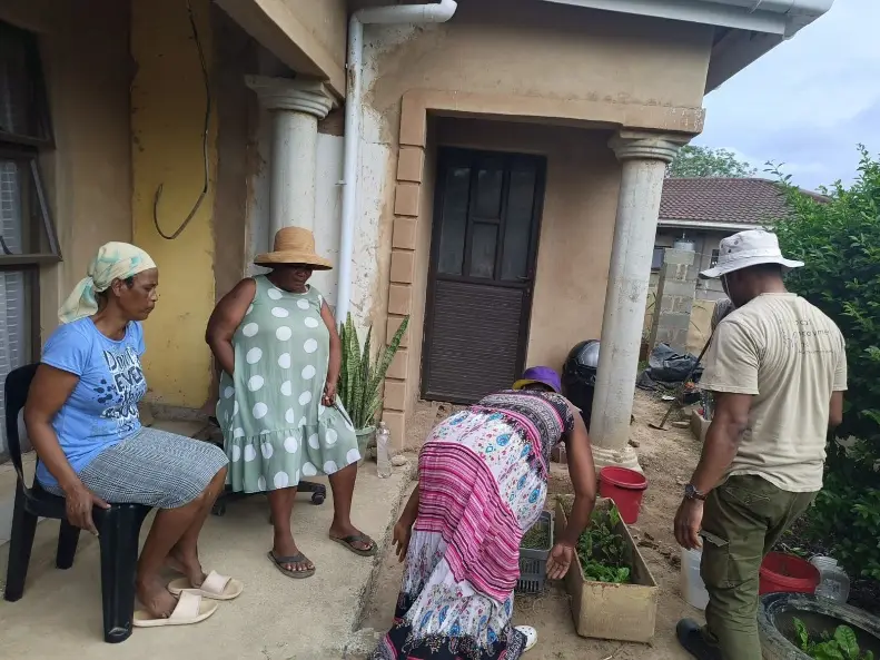 Community gardener showing household members how to plant in their yard